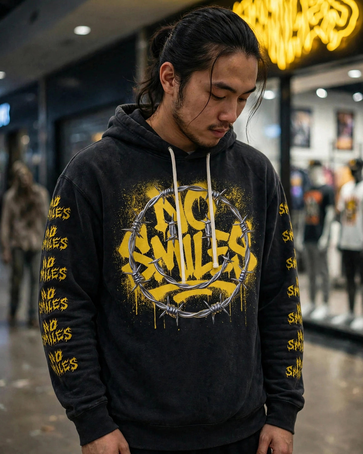 Barbed Wire Smiley no pocket hoodie worn in front of the No Smiles store, looking down, sleeve prints visible