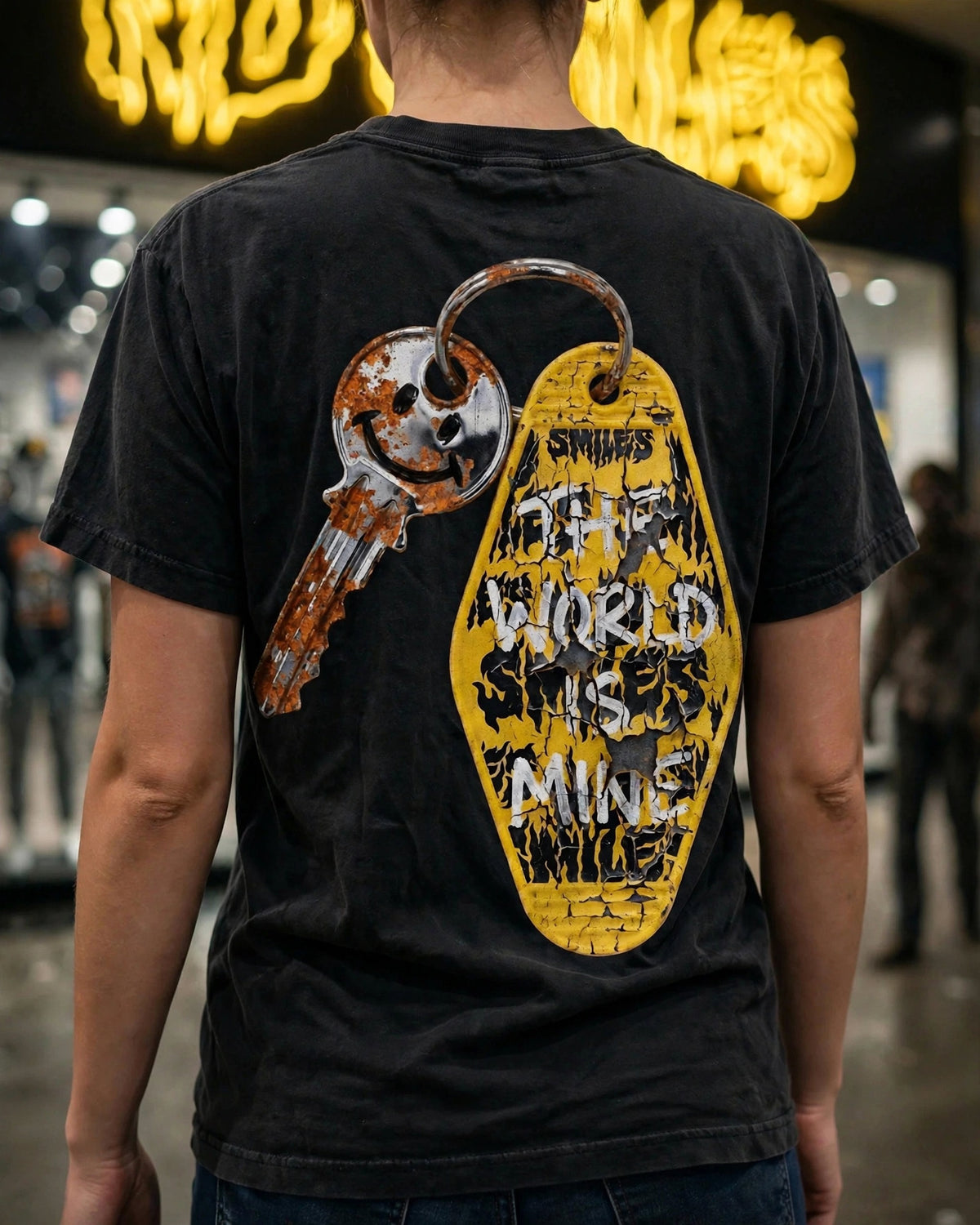 Bought With Bottlecaps tee back print worn in front of the No Smiles store: rusty smiley key and yellow motel key tag